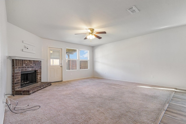 unfurnished living room featuring ceiling fan and a brick fireplace