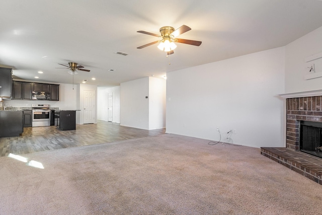 carpeted living room with ceiling fan and a brick fireplace