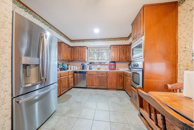 kitchen featuring a textured ceiling, light tile patterned floors, and stainless steel appliances