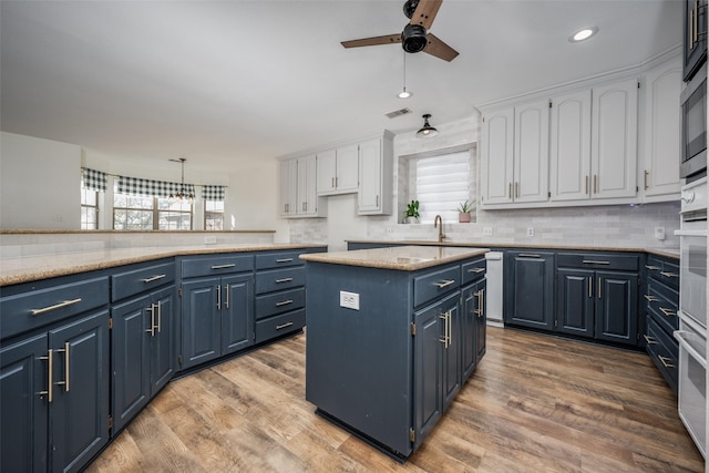 kitchen with blue cabinetry, a center island, white cabinets, and light hardwood / wood-style flooring