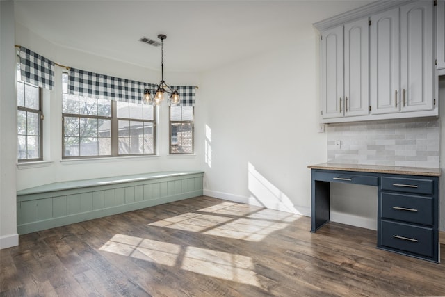 unfurnished dining area featuring an inviting chandelier and dark wood-type flooring