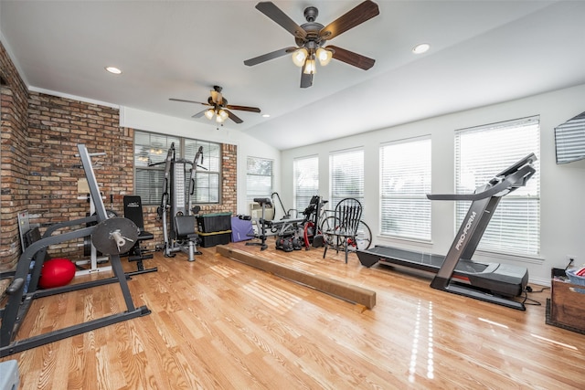 workout room with light hardwood / wood-style flooring, vaulted ceiling, ceiling fan, and brick wall