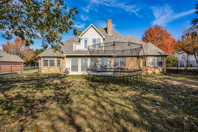 back of house with a yard and a trampoline