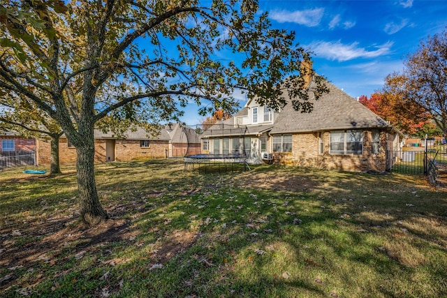 back of property featuring a lawn and a trampoline