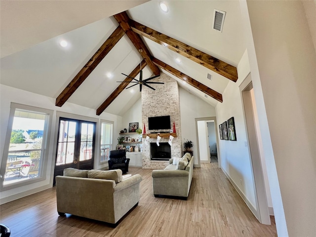 living room featuring ceiling fan, high vaulted ceiling, a fireplace, beamed ceiling, and light wood-type flooring