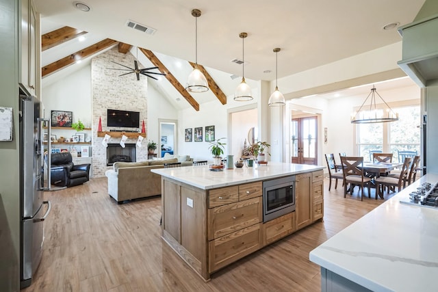 kitchen featuring light stone countertops, appliances with stainless steel finishes, a center island, and pendant lighting