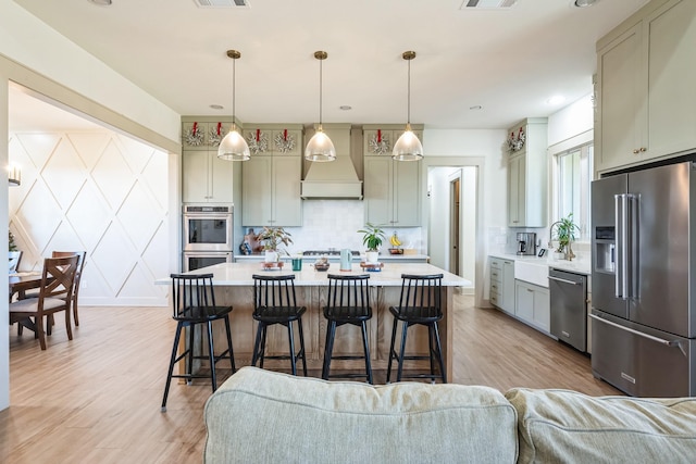 kitchen featuring premium range hood, tasteful backsplash, hanging light fixtures, appliances with stainless steel finishes, and gray cabinets