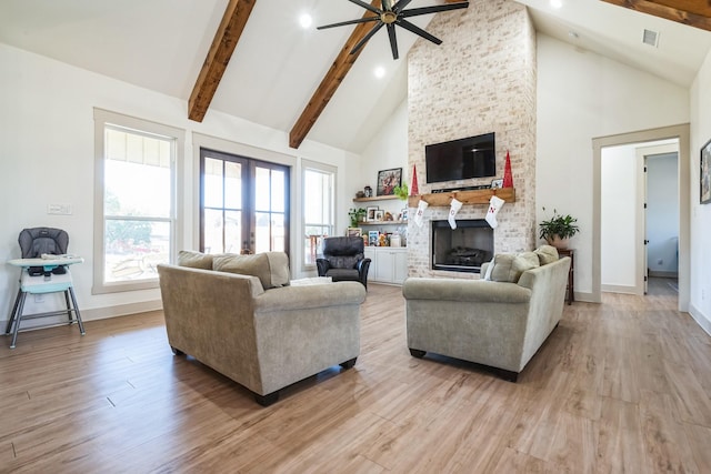 living room with french doors, high vaulted ceiling, a brick fireplace, beamed ceiling, and light hardwood / wood-style floors