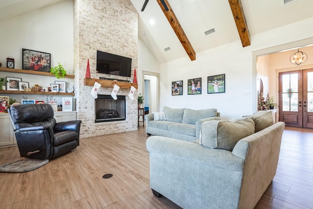 living room with beamed ceiling, a fireplace, high vaulted ceiling, and light hardwood / wood-style flooring