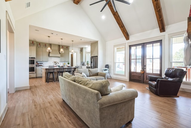 living room with beamed ceiling, high vaulted ceiling, light hardwood / wood-style flooring, and french doors