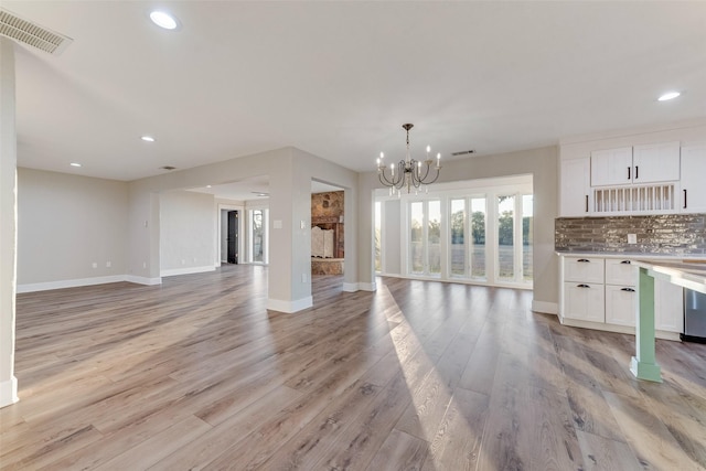 kitchen featuring white cabinetry, an inviting chandelier, light wood-type flooring, and decorative backsplash