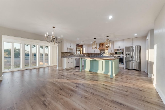 kitchen with hanging light fixtures, a center island, white cabinets, and appliances with stainless steel finishes