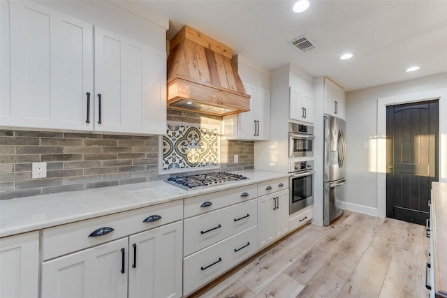 598 Dowell Rd, Rockwall, TX 75032 - kitchen with custom range hood, appliances with stainless steel finishes, white cabinetry, light wood-type flooring, and tasteful backsplash