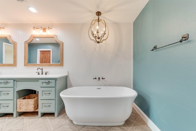 bathroom featuring an inviting chandelier, parquet flooring, vanity, and a bathing tub