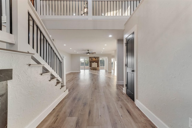 entrance foyer featuring a towering ceiling, ceiling fan, and light wood-type flooring