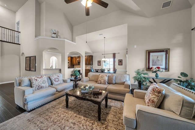 living room featuring ceiling fan with notable chandelier, dark hardwood / wood-style floors, and high vaulted ceiling