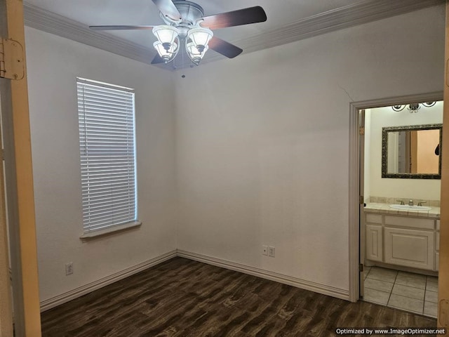 empty room with ceiling fan, sink, crown molding, and dark wood-type flooring