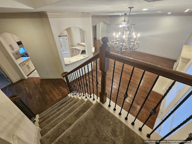 staircase featuring a chandelier, hardwood / wood-style flooring, and ornamental molding