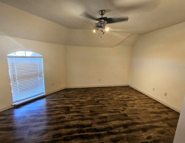 empty room with ceiling fan, dark hardwood / wood-style flooring, and lofted ceiling