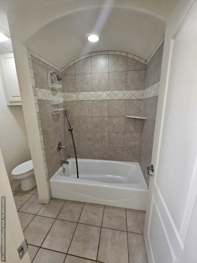 bathroom with tile patterned flooring, toilet, and tiled shower / bath