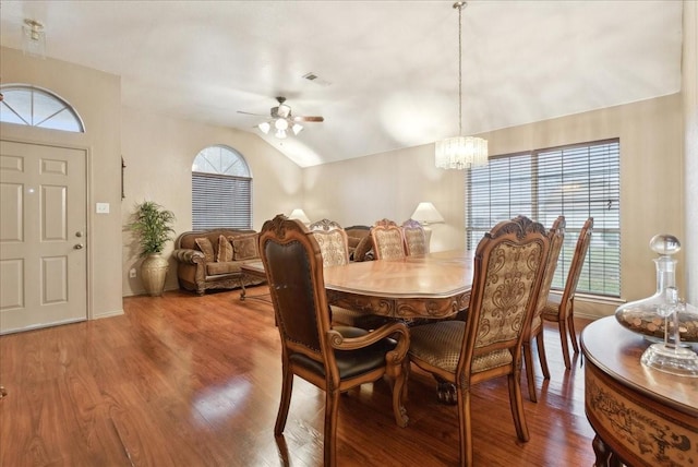 dining room featuring ceiling fan with notable chandelier, hardwood / wood-style flooring, and vaulted ceiling