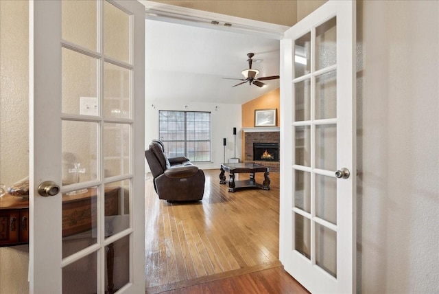 living room with hardwood / wood-style floors, ceiling fan, vaulted ceiling, and french doors