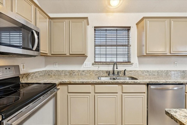 kitchen featuring light brown cabinets, stainless steel appliances, light stone counters, and sink