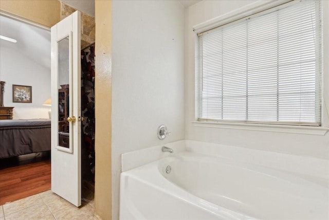 bathroom with a tub to relax in, tile patterned flooring, and vaulted ceiling