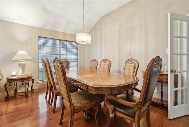 dining space featuring an inviting chandelier, lofted ceiling, and hardwood / wood-style flooring