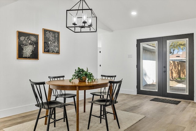 dining space featuring a notable chandelier, lofted ceiling, french doors, and light wood-type flooring