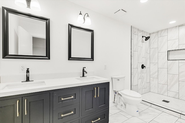 bathroom featuring toilet, a tile shower, and vanity