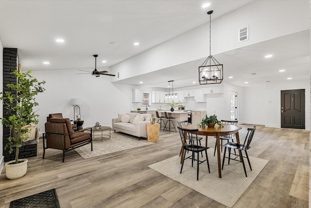 dining room with ceiling fan with notable chandelier and light wood-type flooring