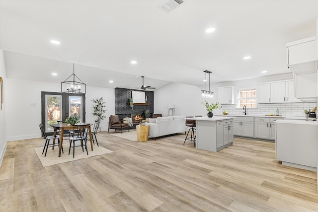 kitchen featuring decorative light fixtures, ceiling fan, a fireplace, a center island, and a breakfast bar