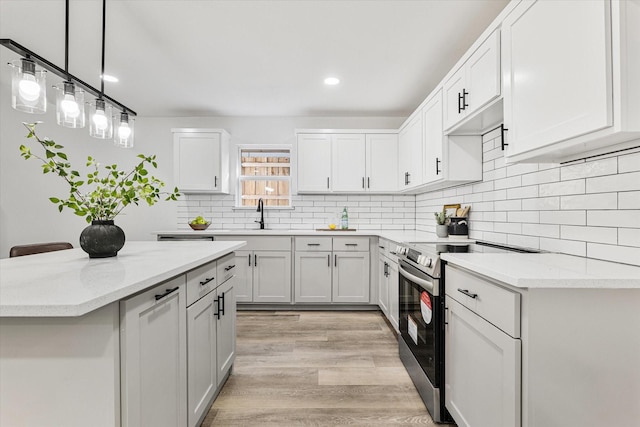 kitchen with hanging light fixtures, white cabinets, light stone countertops, and stainless steel range with electric cooktop