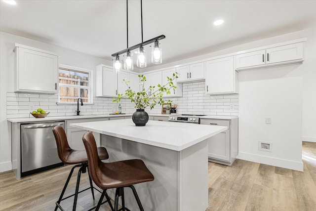 kitchen featuring white cabinetry, a center island, stainless steel appliances, and light wood-type flooring