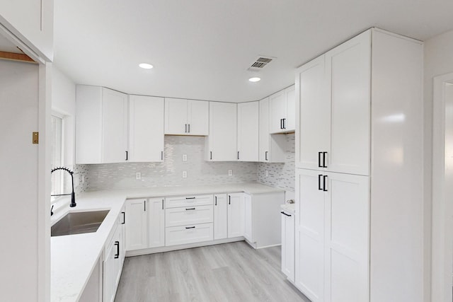 kitchen featuring light hardwood / wood-style floors, white cabinetry, and sink