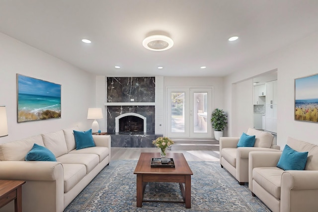 living room with a high end fireplace and wood-type flooring