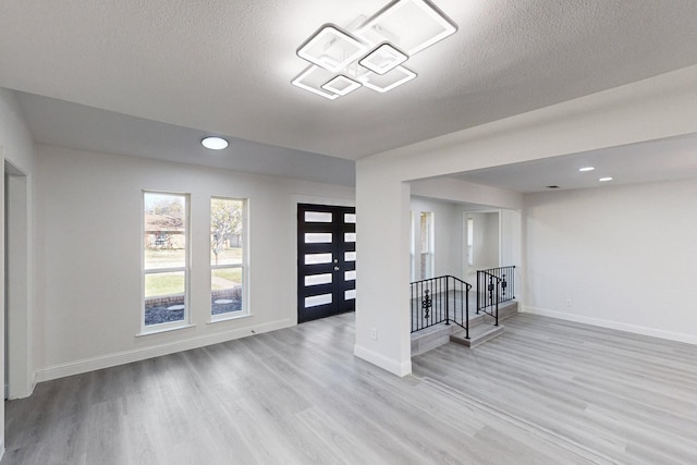 interior space with french doors, light hardwood / wood-style flooring, and a textured ceiling