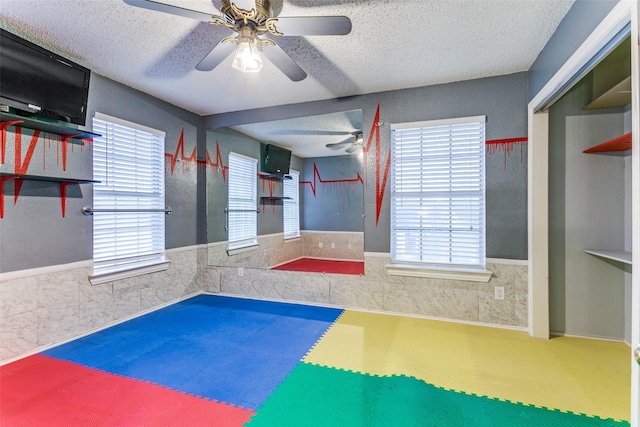 exercise room featuring ceiling fan and a textured ceiling