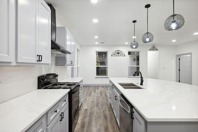 kitchen with black / electric stove, sink, hanging light fixtures, a kitchen island with sink, and wall chimney exhaust hood