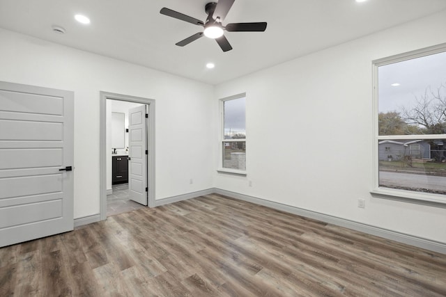 unfurnished bedroom featuring ceiling fan, ensuite bathroom, and light hardwood / wood-style floors