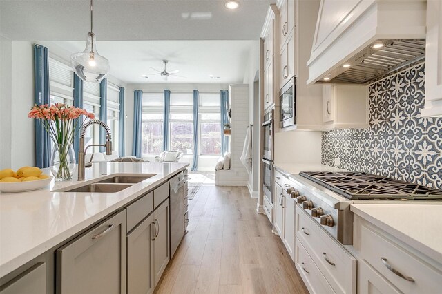 kitchen featuring premium range hood, sink, white cabinets, and appliances with stainless steel finishes