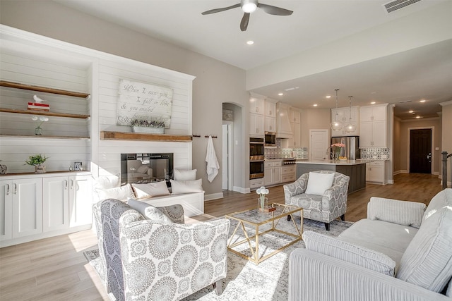 living room featuring ceiling fan, light hardwood / wood-style flooring, and sink