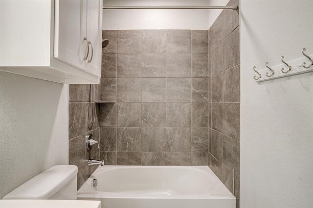 bathroom featuring toilet and tiled shower / bath