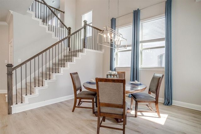 dining area with light hardwood / wood-style floors, a high ceiling, and a notable chandelier