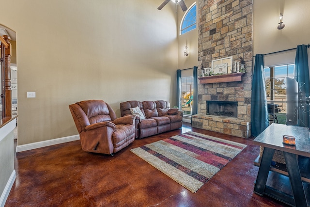 living room with a towering ceiling, a fireplace, and ceiling fan