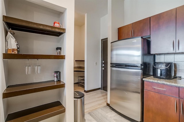 kitchen featuring stainless steel refrigerator, decorative backsplash, and light hardwood / wood-style floors