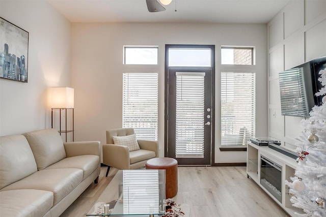 living room featuring ceiling fan, plenty of natural light, and light hardwood / wood-style floors