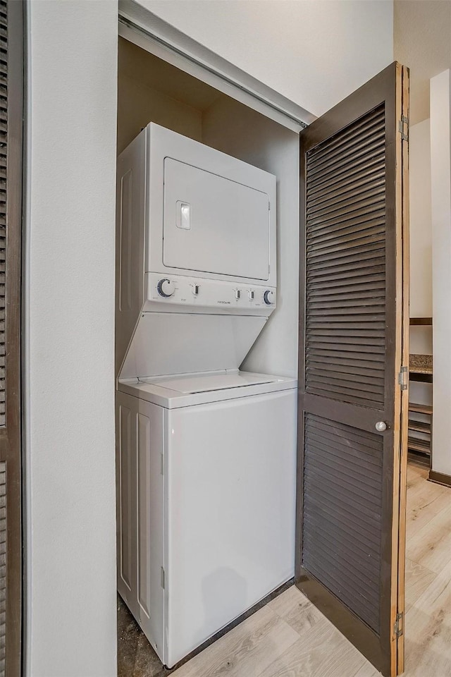 laundry area with light hardwood / wood-style floors and stacked washer and dryer