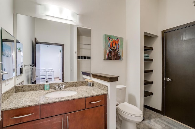 bathroom featuring built in shelves, vanity, toilet, and walk in shower